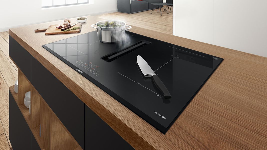 Table induction aspirante Bosch sur un îlot en bois, couteau posé sur la vitrocéramique