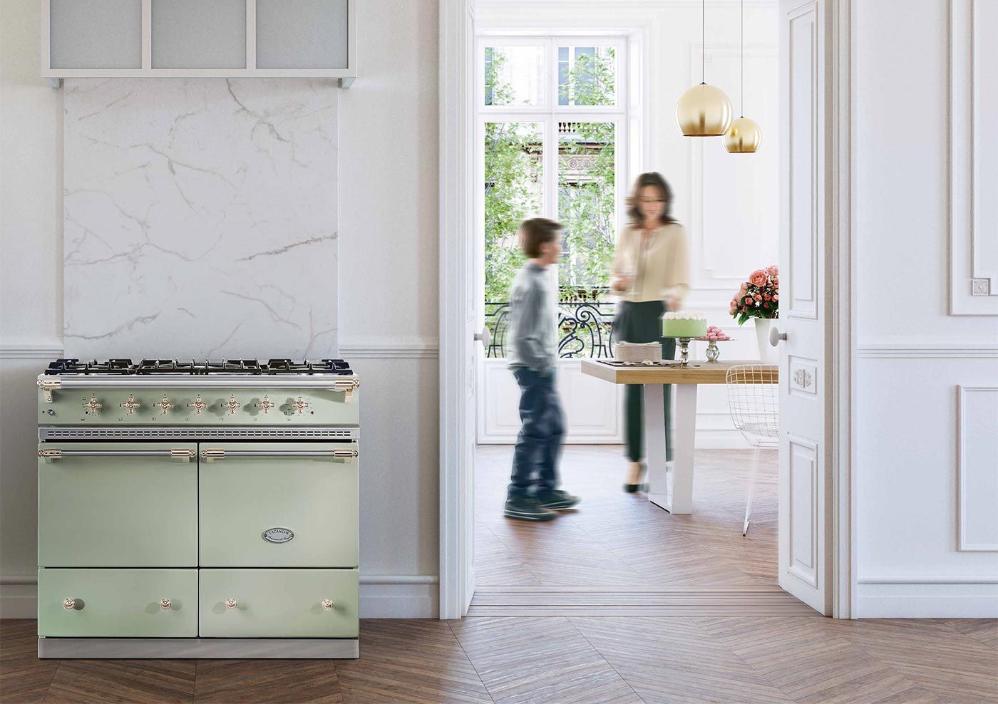Piano de cuisson Lacanche vert amande à deux fours, crédence en marbre, dans un appartement parisien à moulures et parquet à chevrons