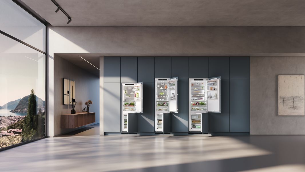 Trois réfrigérateurs Liebherr intégrables XL et XXL ouverts dans un mur de colonnes vert-bleu