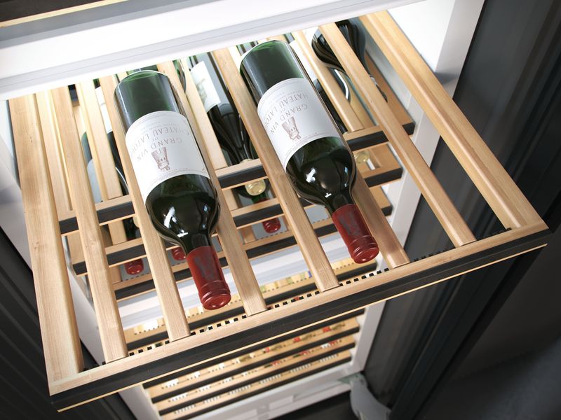 Clayette en bois d’une cave à vin Miele sortie, bouteilles de vin rouge couchées