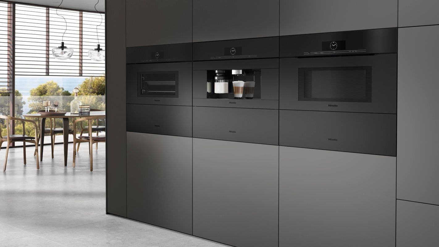 Colonne d’appareils encastrables Miele gris graphite, four, machine à café et four compact, dans une cuisine ouverte