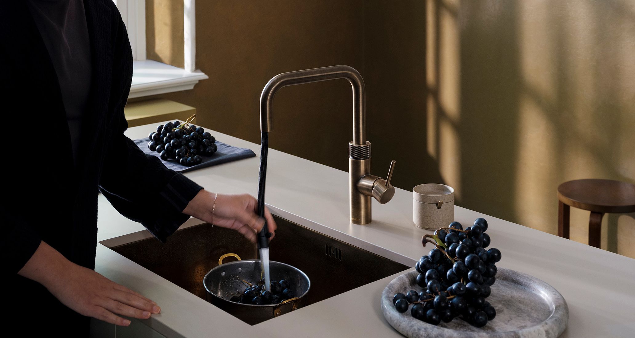 Robinet Quooker Flex Square laiton patiné, douchette extractible rinçant des myrtilles au-dessus d’un évier