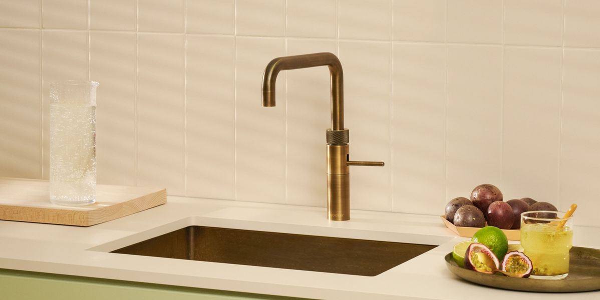 Robinet Quooker Fusion Square laiton patiné sur un évier sous plan, fruits de la passion et eau pétillante
